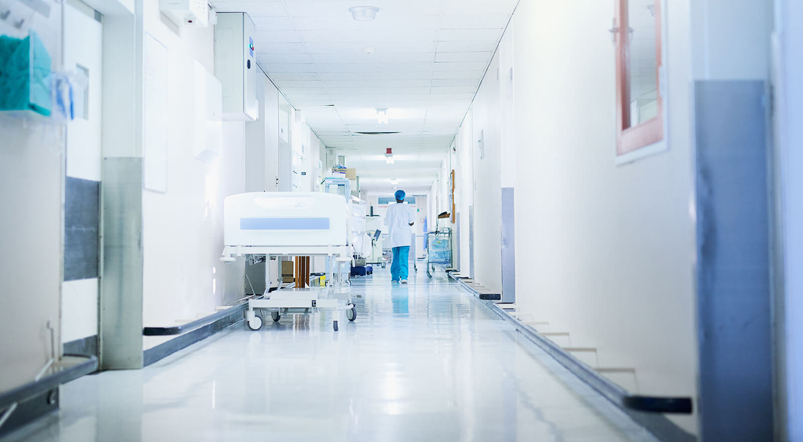 Image of a doctor walking down an empty hospital corridor